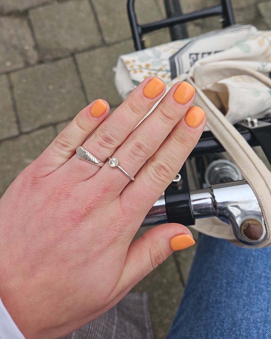 Hand met oranje gelakte nagels aan het stuur van een fiets